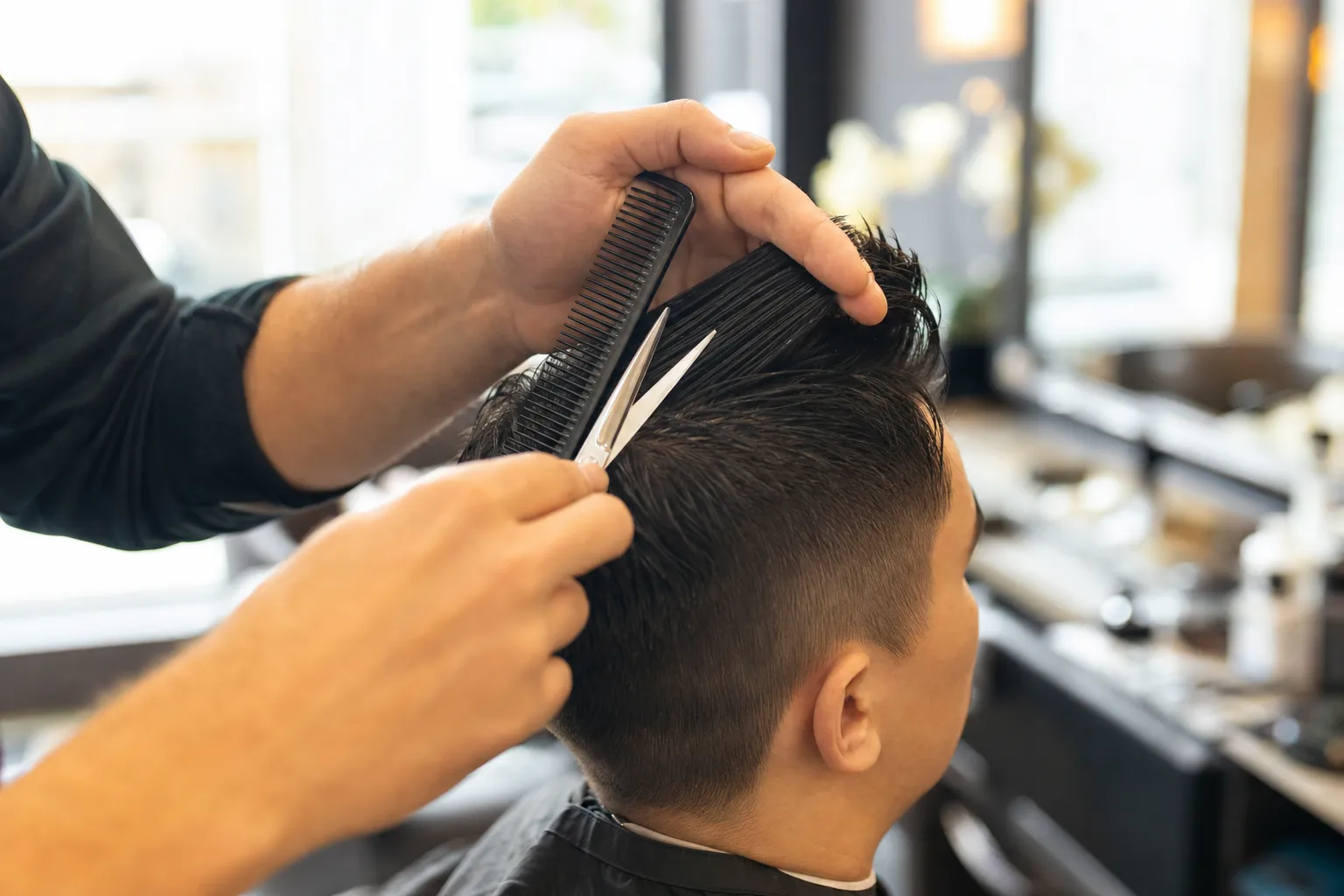 Scissors and comb working through a client's hair mid-cut