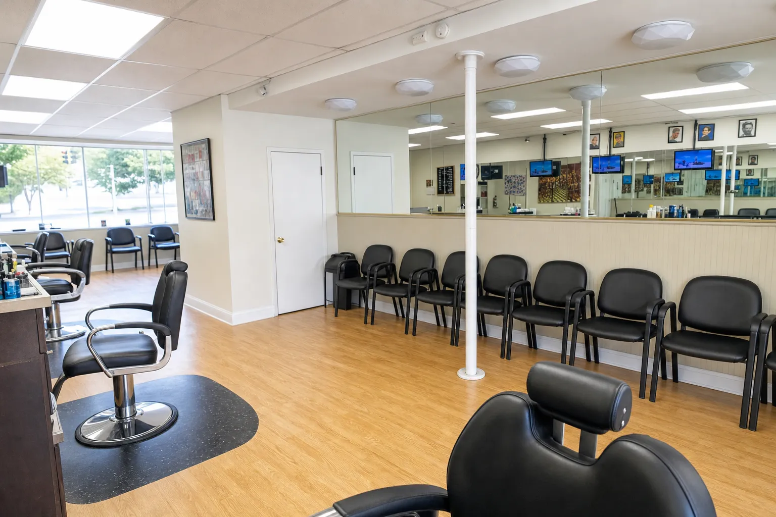 Inside Camp Ave Barbershop — wall mirrors, black chairs, light wood floor and white columns