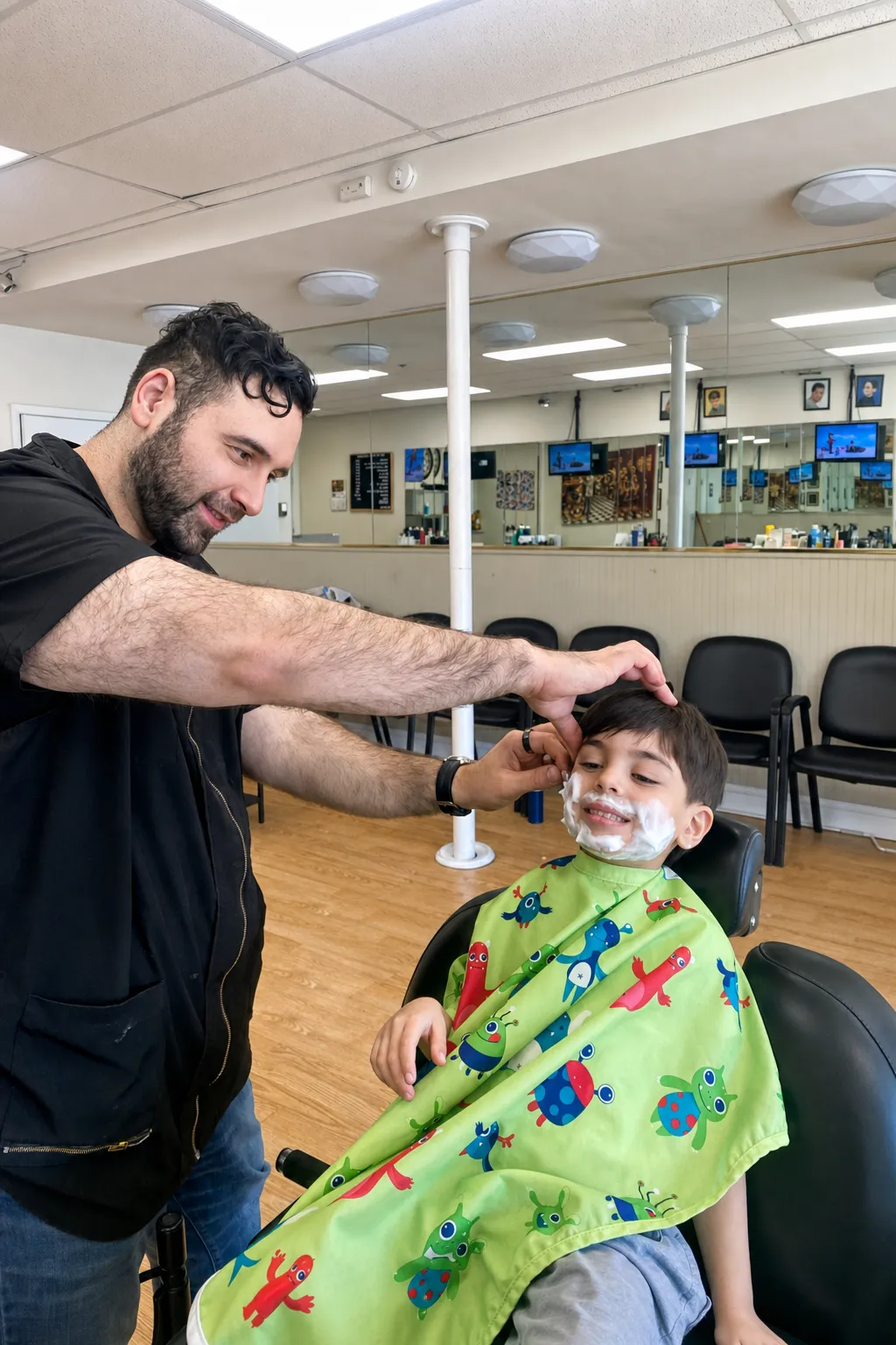 Ruben giving a young boy a pretend hot-lather shave under the shop's green monster-print cape